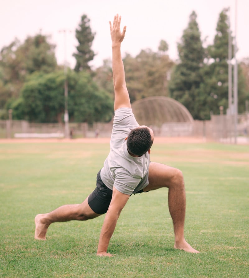 Un homme dans un stade fait des étirements et exercice de mobilité du dos